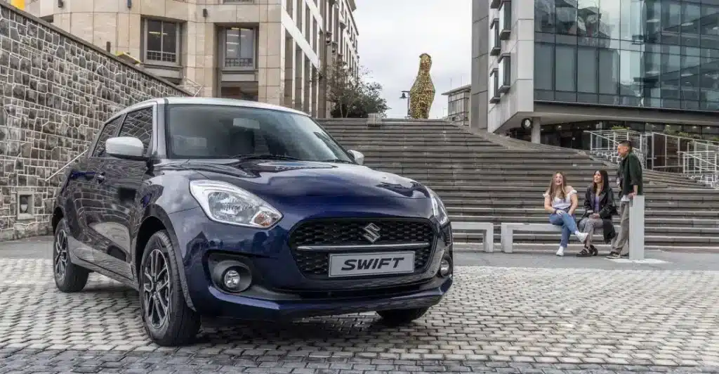 Blue Suzuki Swift, parked on a cobbled street in front of brick stairs